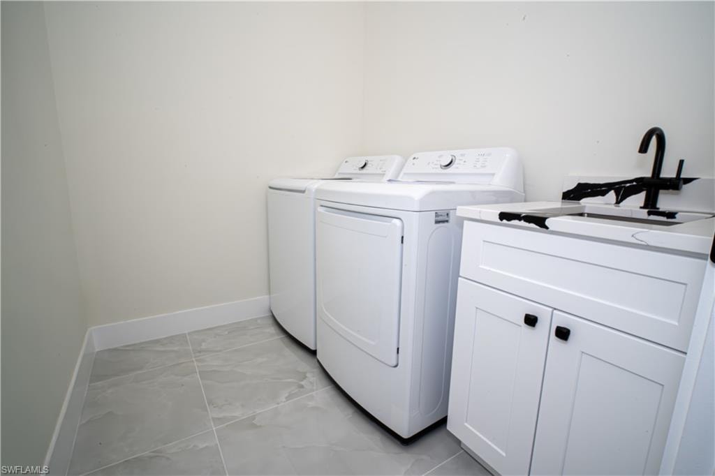 Laundry room with cabinet space, washer and dryer, and light marble finish floors