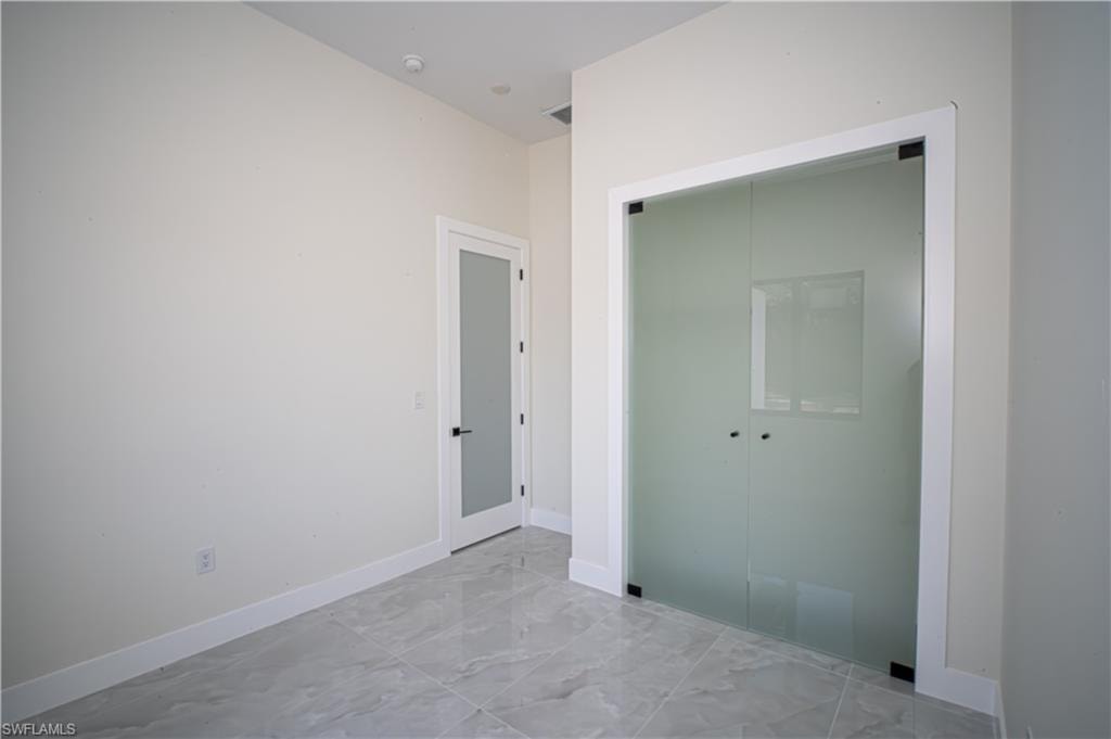 Unfurnished bedroom featuring light marble finish flooring and a closet