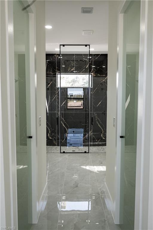 Bathroom with marble tiled flooring, a marble finish shower, and recessed lighting