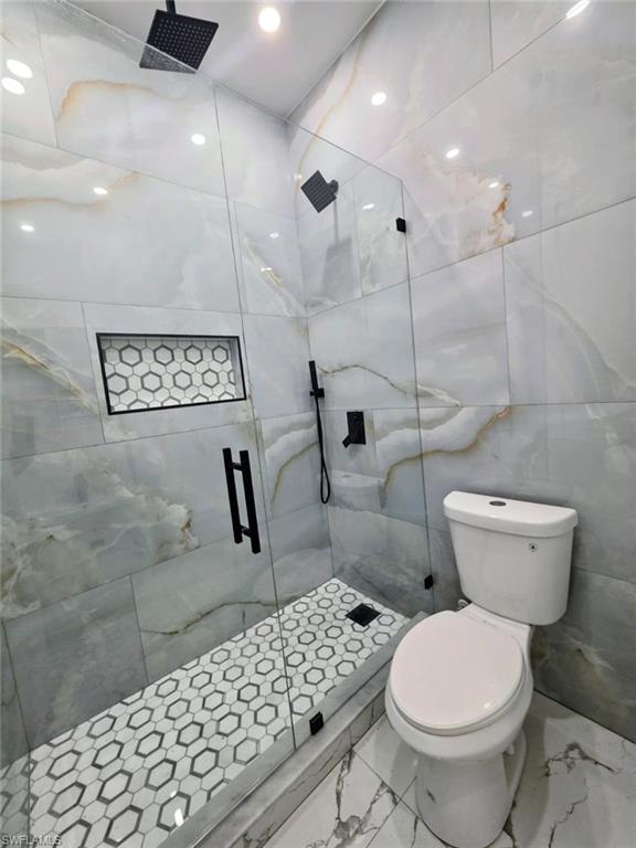 Bathroom featuring a marble finish shower, tile walls, marble tiled flooring, and recessed lighting