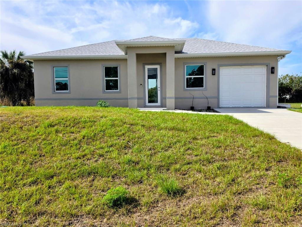 View of front of house with a garage, a front lawn, and stucco siding