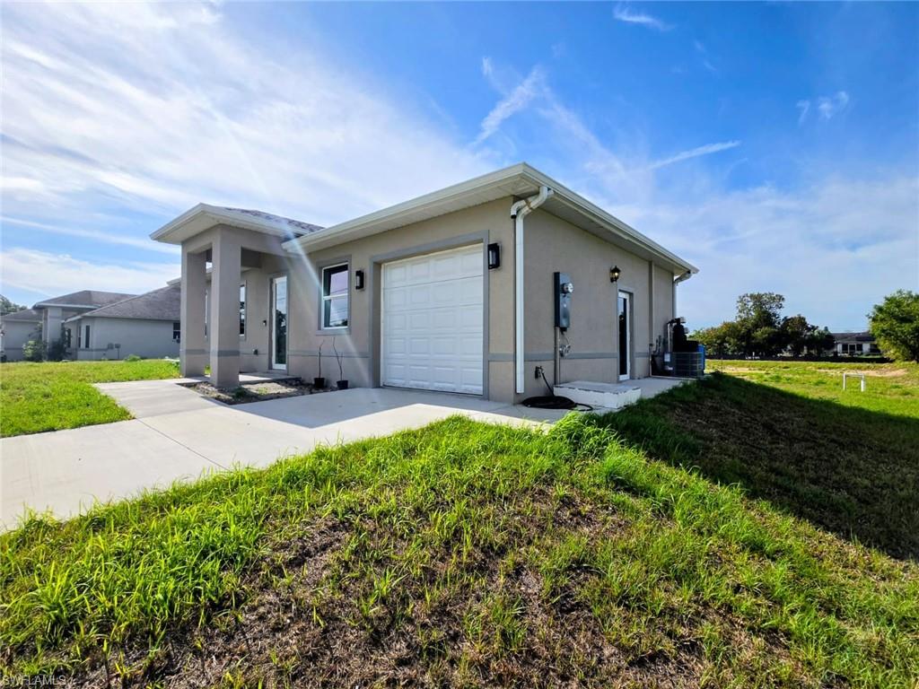 View of front of property with a garage, a front yard, stucco siding, and concrete driveway