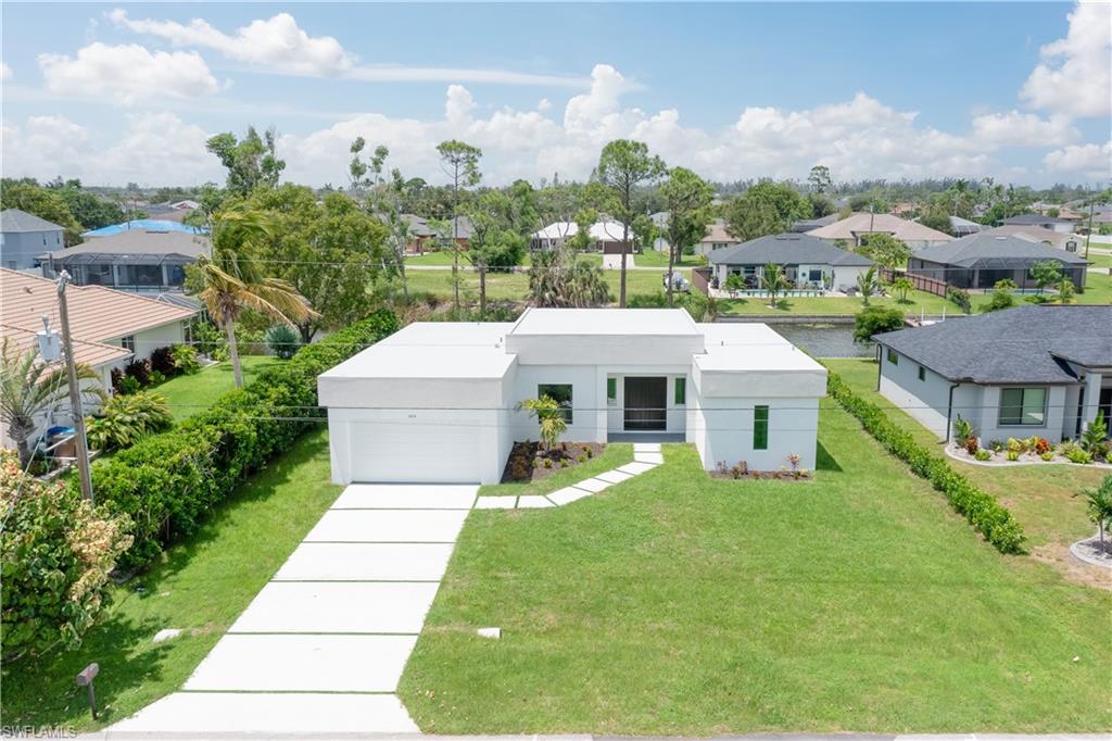 View of front facade with driveway, a residential view, a front lawn, and stucco siding