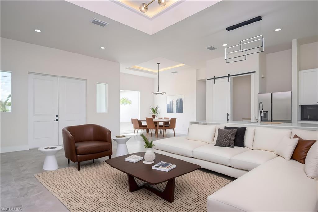 Living area with a barn door, recessed lighting, and a high tray ceiling