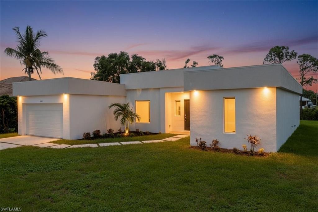 Modern home with a front yard, a garage, and concrete driveway