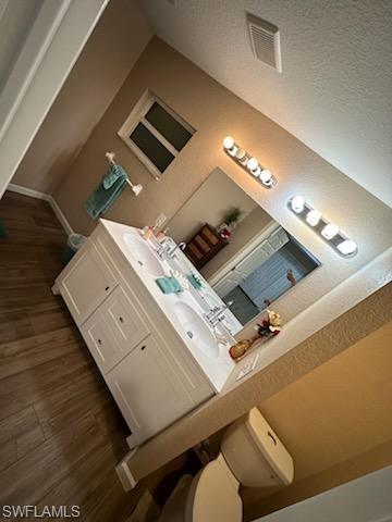 Bathroom with hardwood / wood-style floors, vanity, and toilet