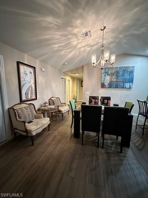 Dining room with vaulted ceiling, a chandelier, and hardwood / wood-style floors