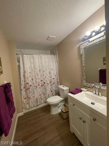 Bathroom with toilet, vanity, a textured ceiling, and hardwood / wood-style floors