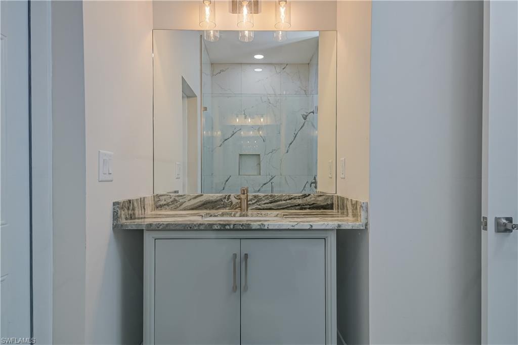Full bath with vanity and a marble finish shower