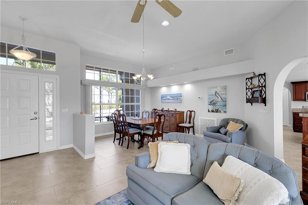 Living area featuring arched walkway, ceiling fan, marble-look tile floor and volume ceiling