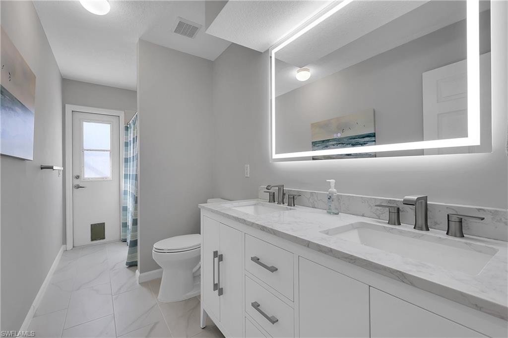 Hall bath matches the primary bath, featuring double vanity, curtained shower/tub, cabana door to pool area and light marble finish floors