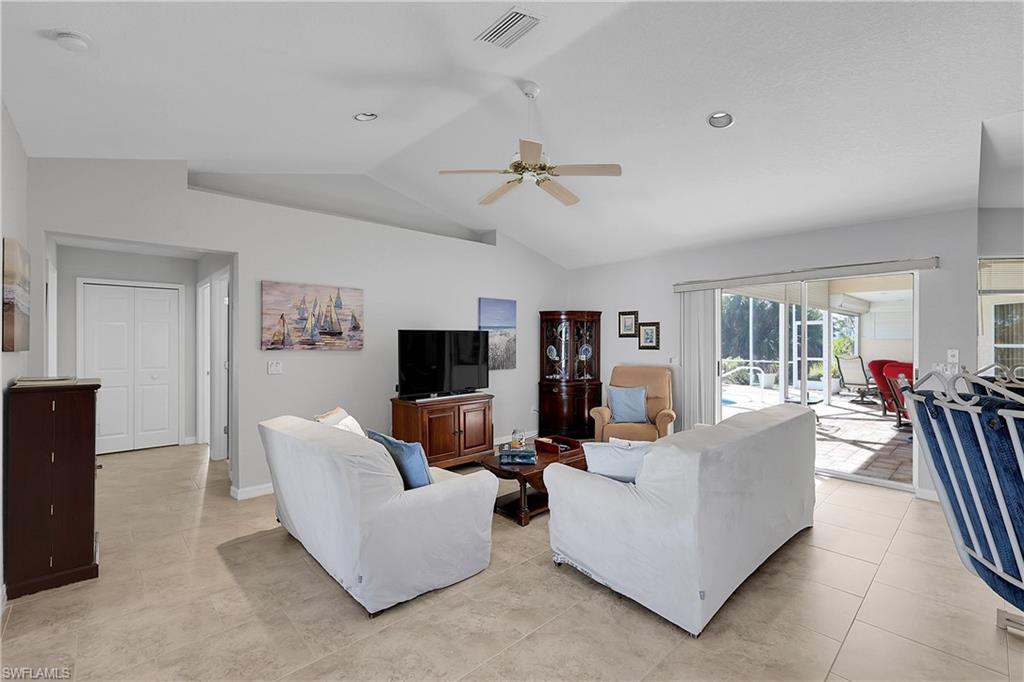 Family room featuring vaulted ceiling, a ceiling fan, display shelf and light tile patterned floors