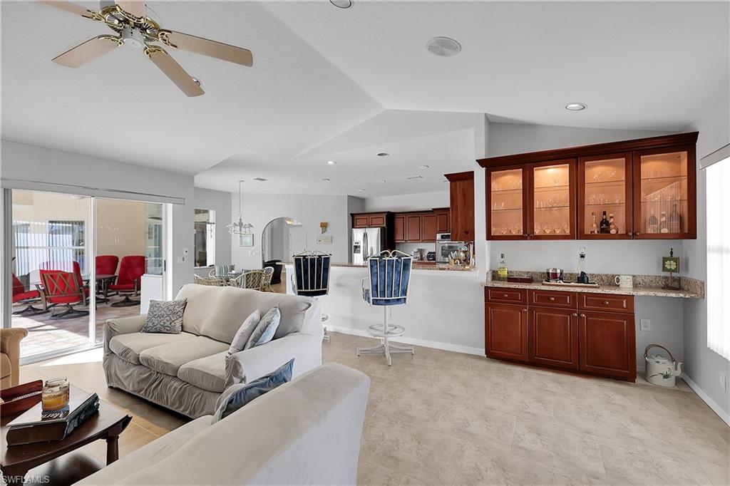 2nd living area featuring ceiling fan, vaulted ceiling, and bar with glass front upper cabinets for display