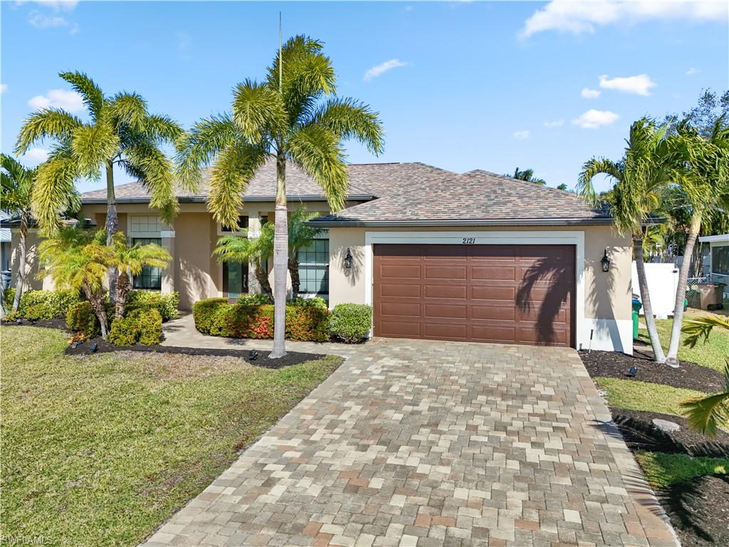 Ranch-style house featuring decorative driveway, a front lawn, stucco siding, and an attached garage