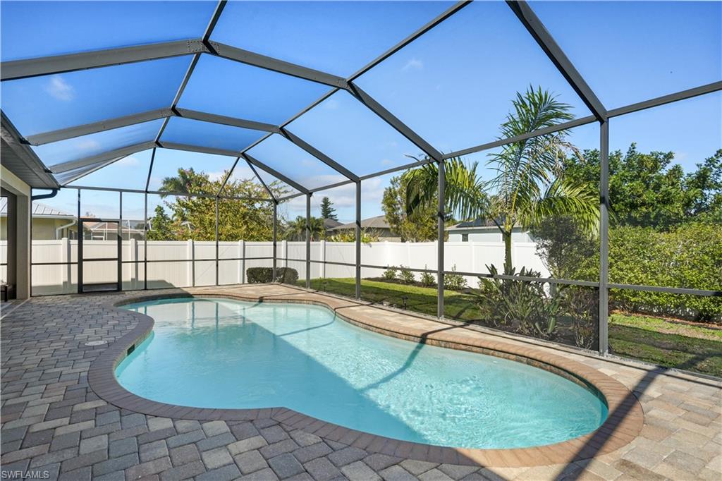 View of pool with glass enclosure, a sunroom, a fenced backyard, and patio surround
