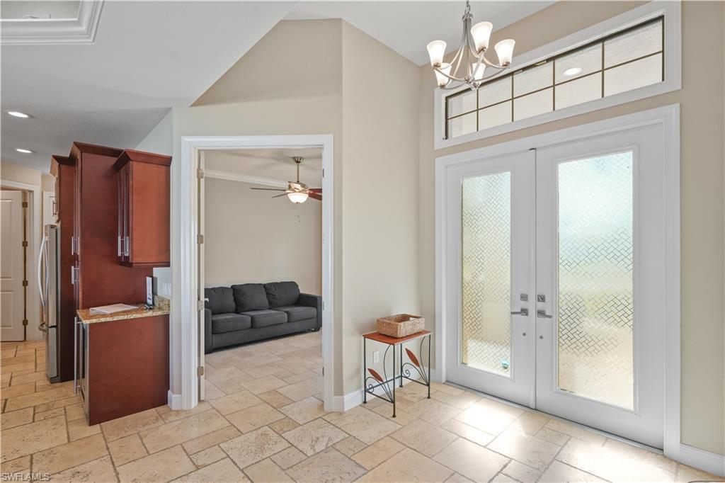 Doorway to outside with stone tile floors, french doors, suspended lighting, and a ceiling fan