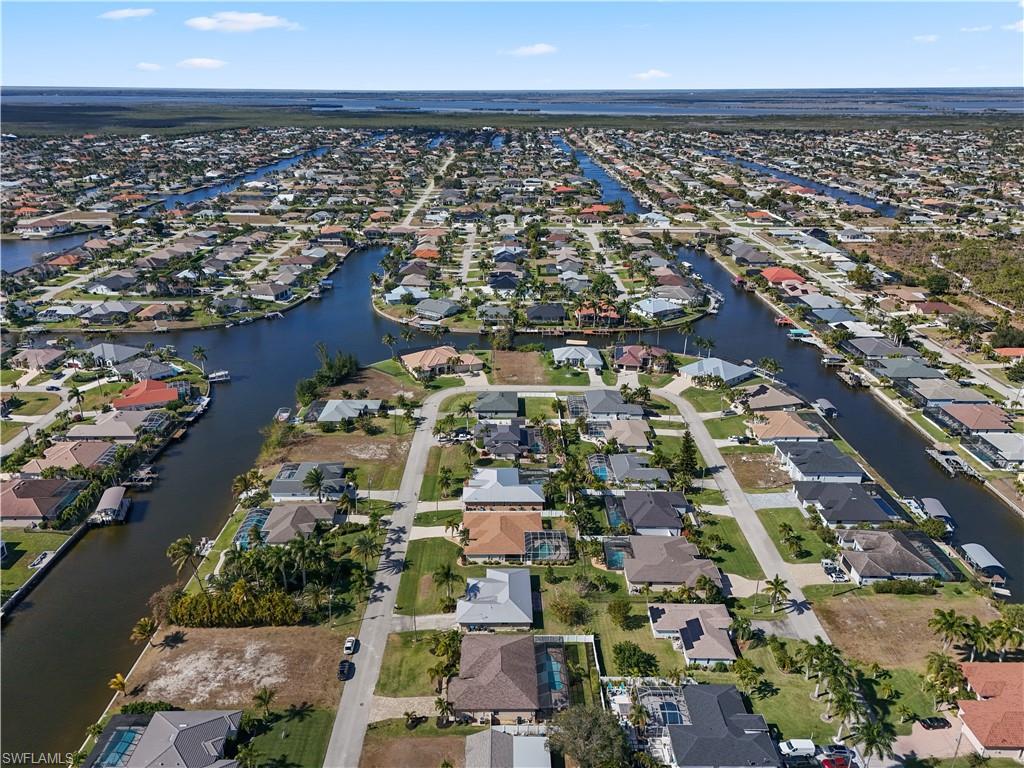 Aerial view of property and surrounding area featuring nearby suburban area and a large body of water