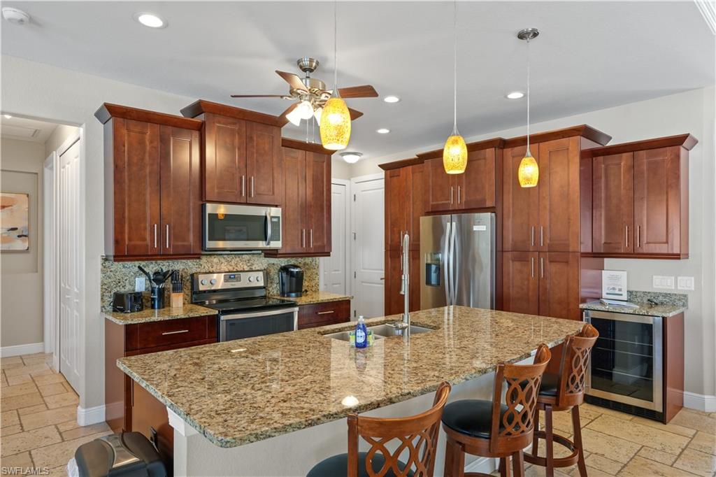 Kitchen with stone tile floors, a kitchen bar, stainless steel appliances, and hanging light fixtures