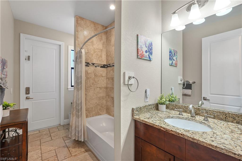 Full bath with vanity, stone tile flooring, and shower / bath combo