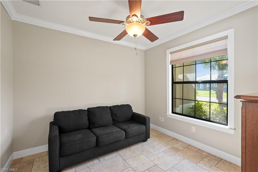 Living area with stone tile floors, crown molding, and ceiling fan