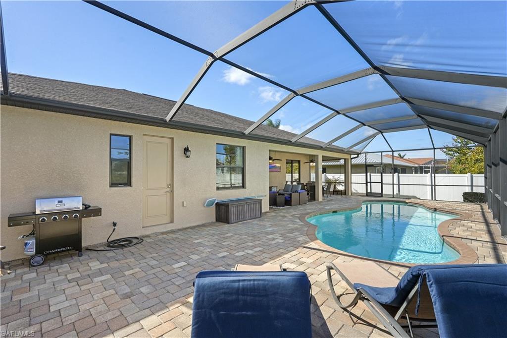 View of swimming pool featuring a sunroom, patio surround, a lanai, and grilling area