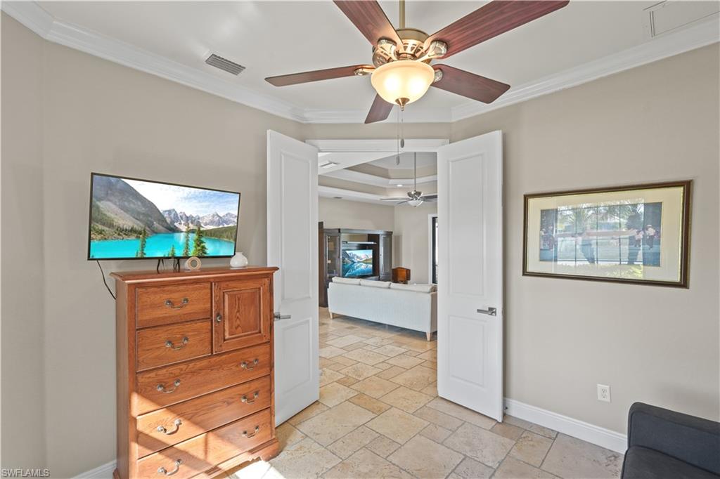 Bedroom with crown molding, stone tile flooring, and ceiling fan