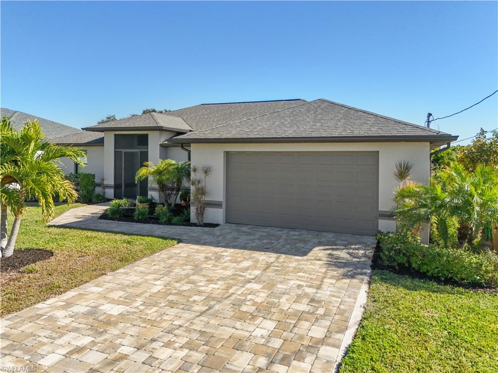 View of front of home featuring stucco siding, decorative driveway, a shingled roof, and a front yard