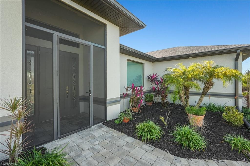 Doorway to property with stucco siding and roof with shingles