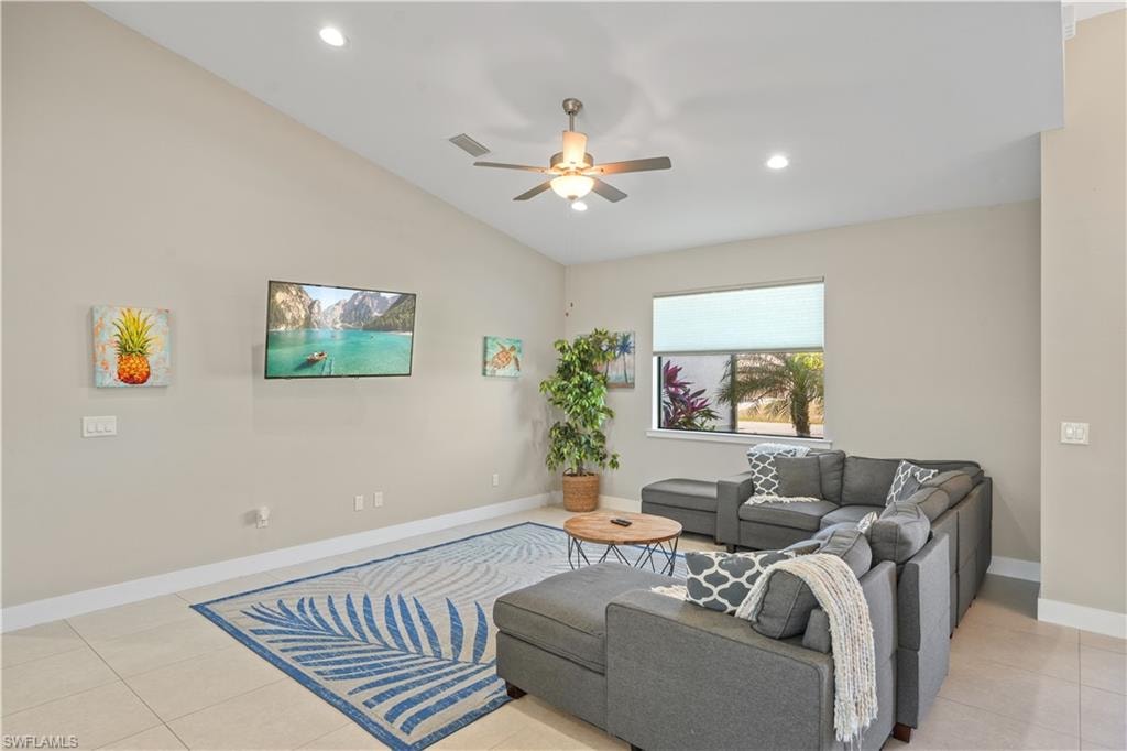 Living area featuring light tile patterned flooring, ceiling fan, vaulted ceiling, and recessed lighting