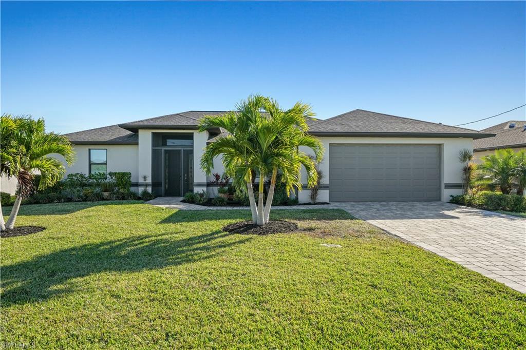 View of front of property featuring stucco siding, a front yard, decorative driveway, an attached garage, and roof with shingles
