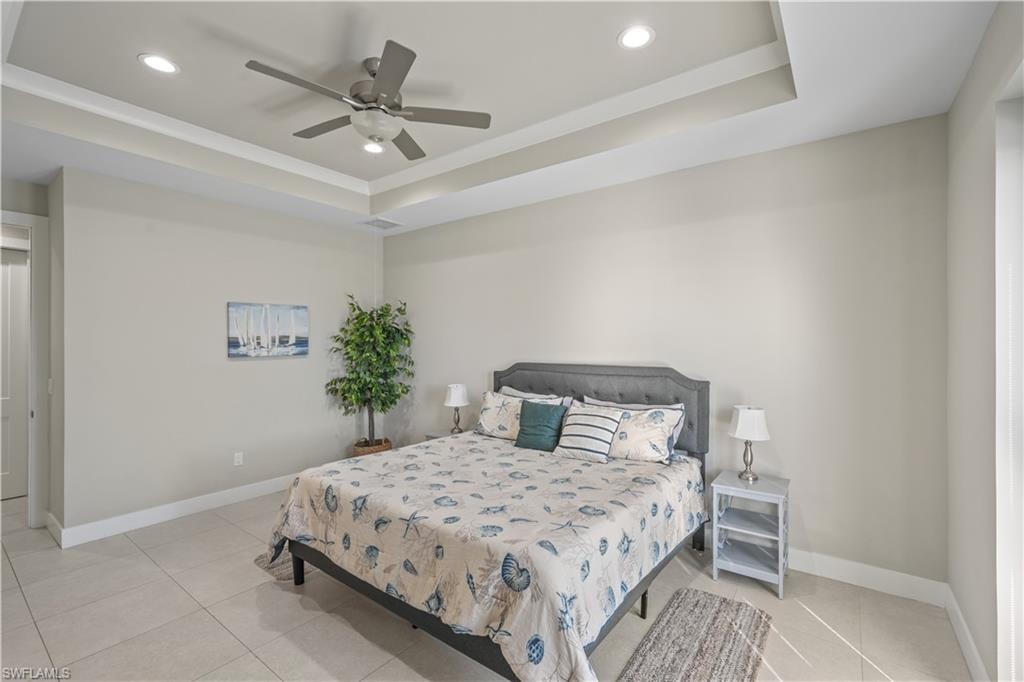 Bedroom featuring a tray ceiling, recessed lighting, a ceiling fan, and light tile patterned floors
