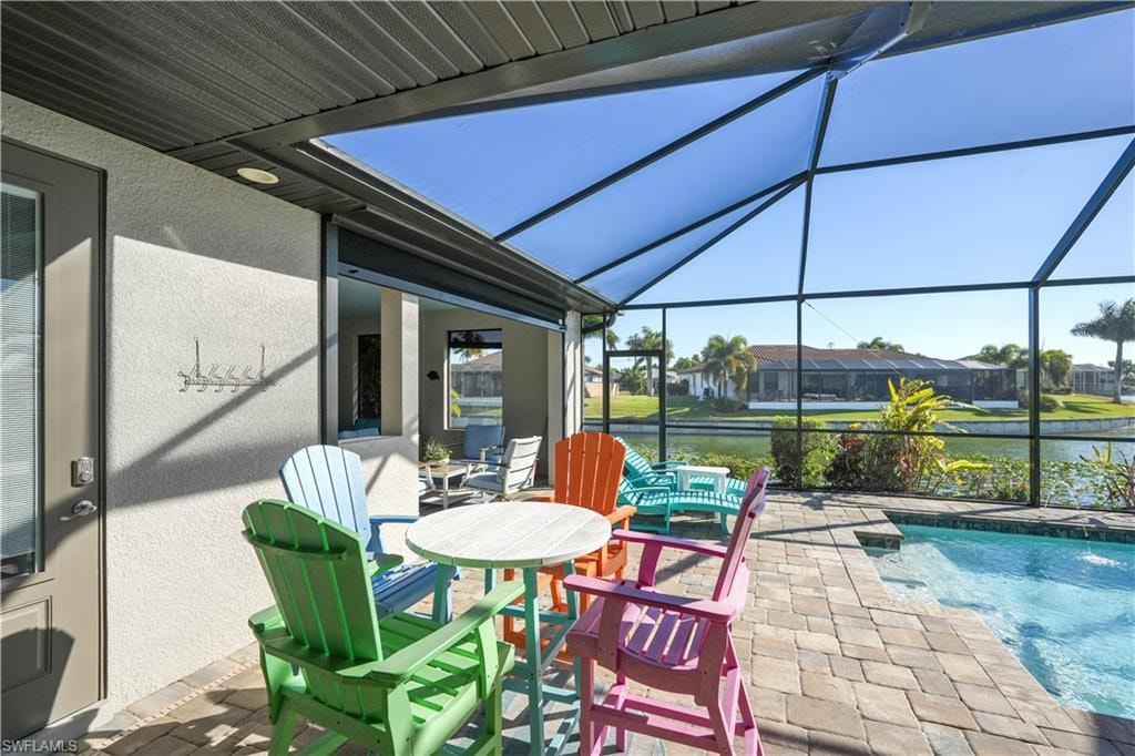 View of patio / terrace featuring a sunroom, glass enclosure, an outdoor pool, and a water view
