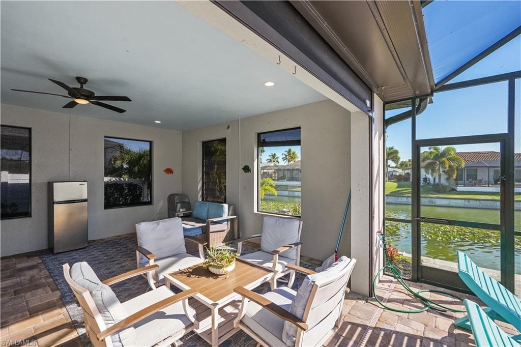 Sunroom with outdoor lounge area, a ceiling fan, a water view, and a patio