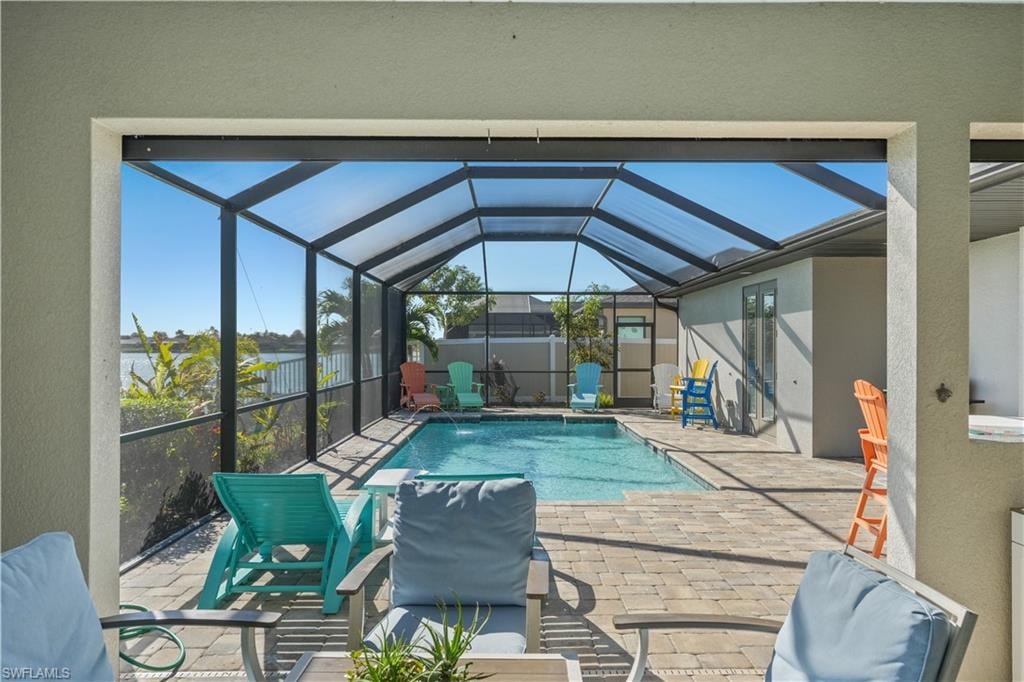 View of pool with a sunroom, patio surround, and glass enclosure