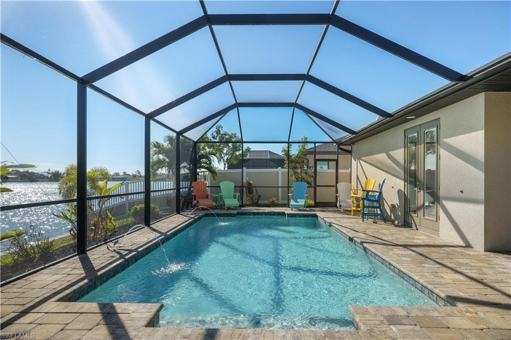 View of swimming pool featuring a lanai, patio surround, a sunroom, and a water view