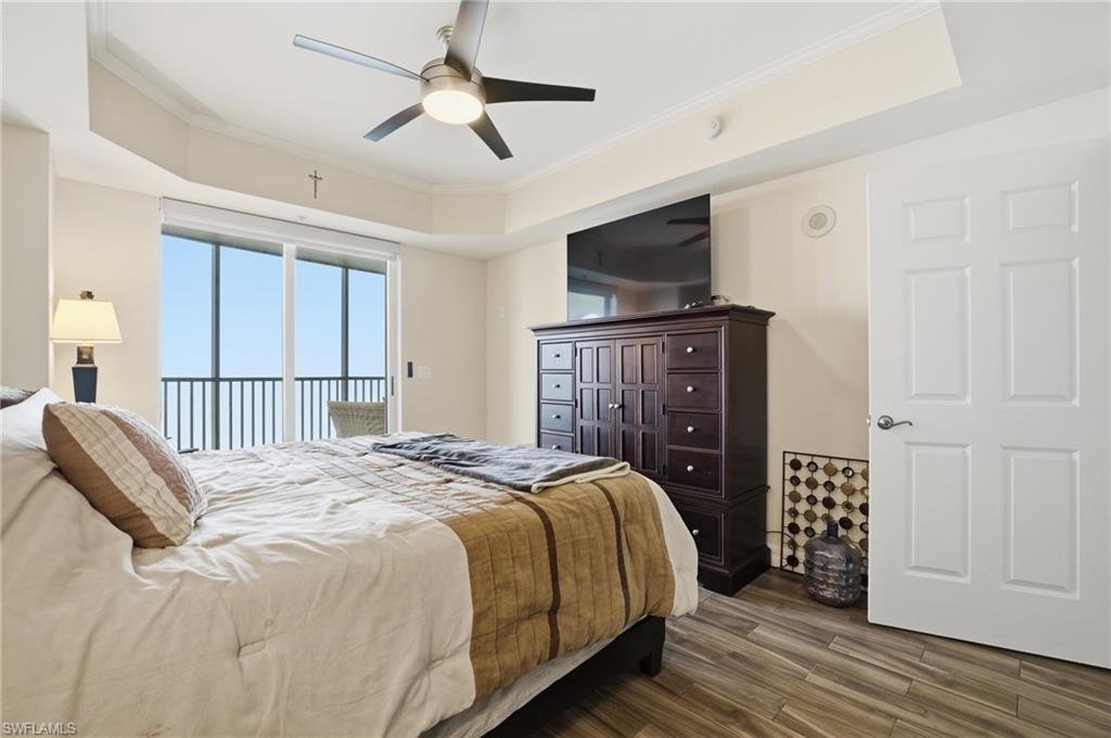 Bedroom with crown molding, access to exterior, wood finished floors, and a raised ceiling