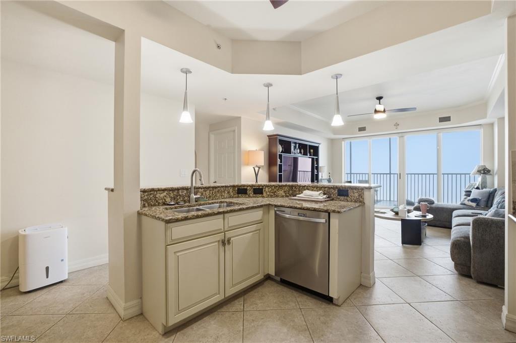 Kitchen with open floor plan, ceiling fan, stainless steel dishwasher, decorative light fixtures, and light stone countertops