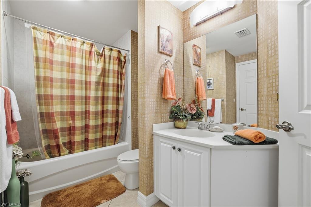 Bathroom with shower / bath combination with curtain, vanity, and light tile patterned floors