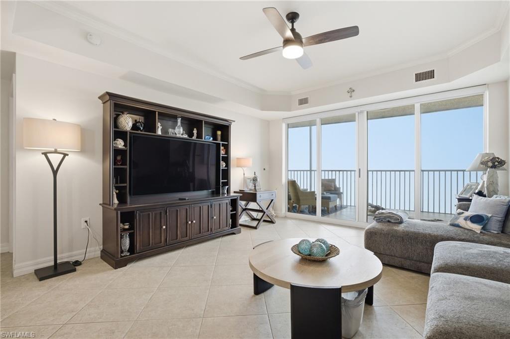 Living room featuring light tile patterned flooring, crown molding, and a ceiling fan