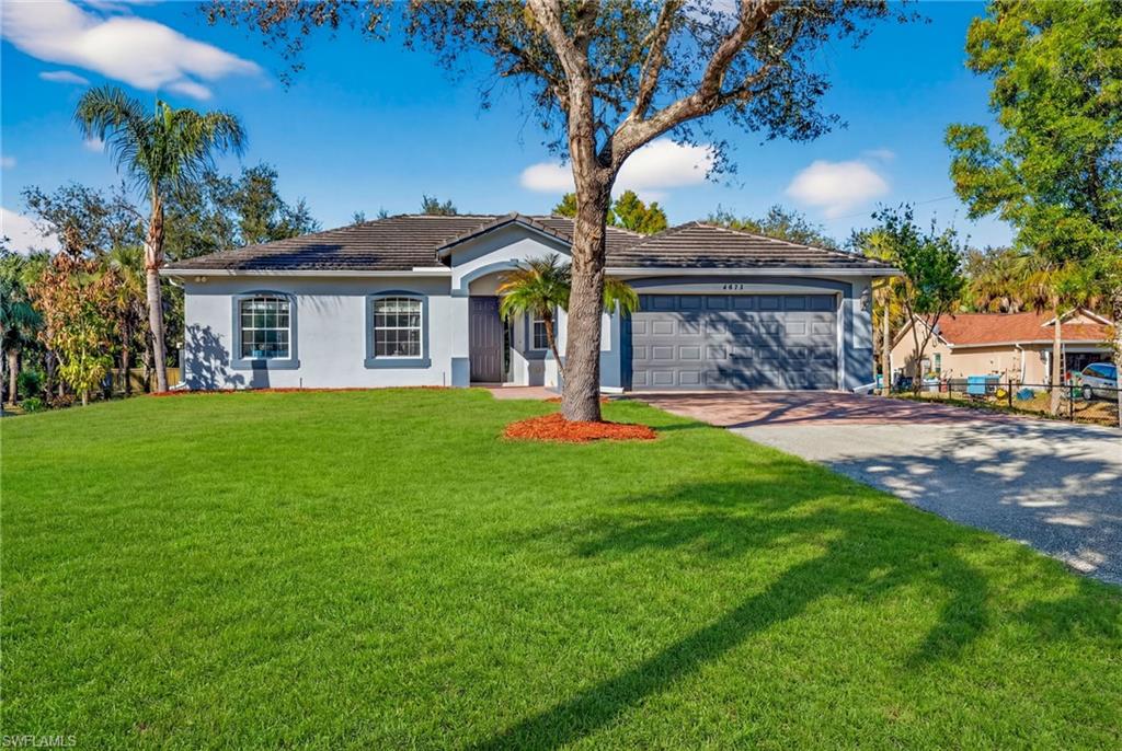 Ranch-style house with driveway, a front yard, stucco siding, a garage, and a tile roof