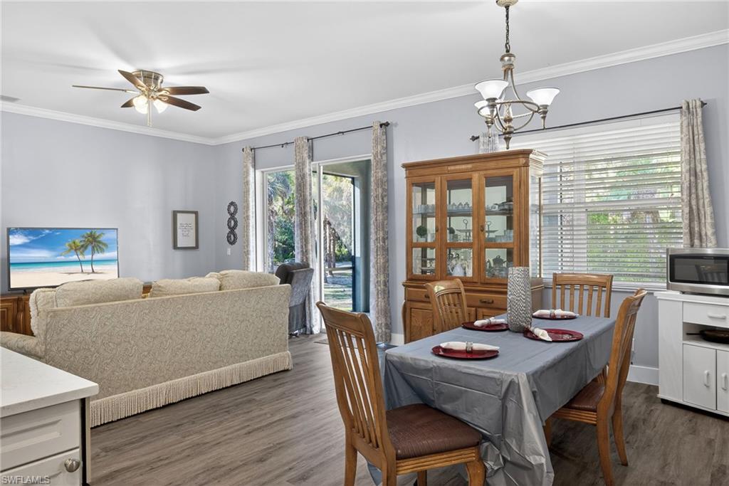 Dining room with ornamental molding, hanging lights, dark wood finished floors, and ceiling fan