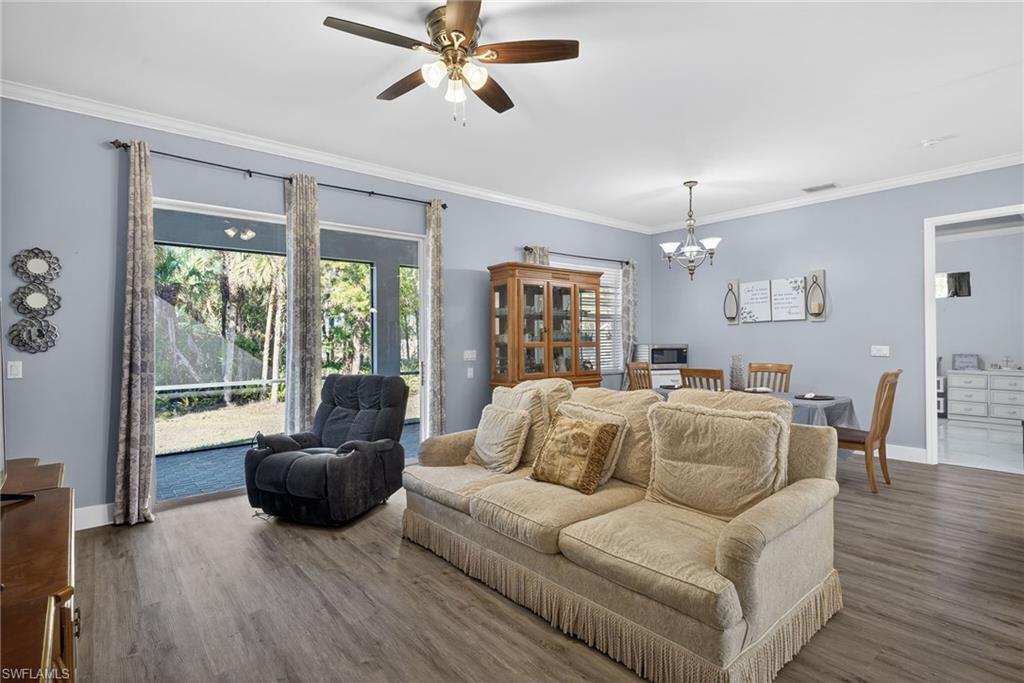 Living room featuring hanging lights, wood finished floors, crown molding, and ceiling fan