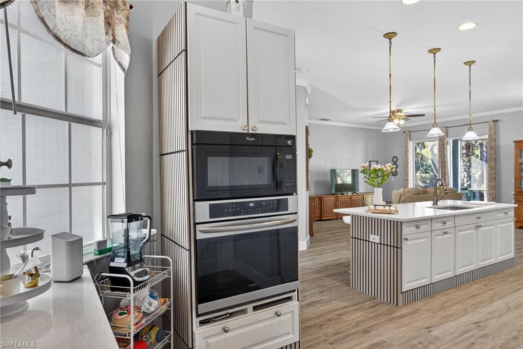 Kitchen featuring white cabinets, crown molding, decorative light fixtures, stainless steel oven, and black microwave