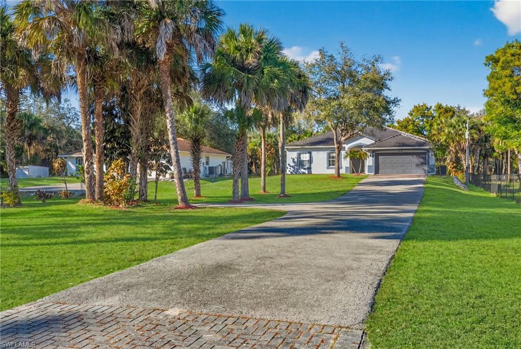 View of front of property with driveway, a front yard, and a garage