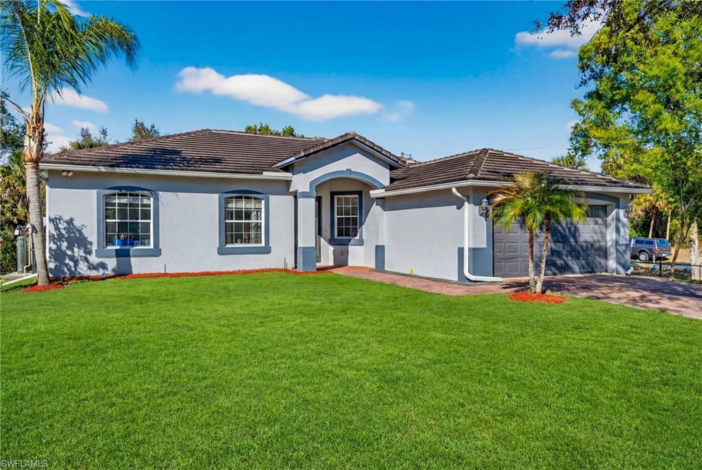 View of front of house featuring a front lawn, an attached garage, stucco siding, and driveway