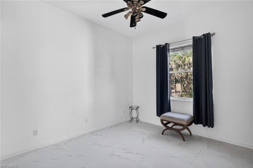Spare room with marble look tile flooring and a ceiling fan