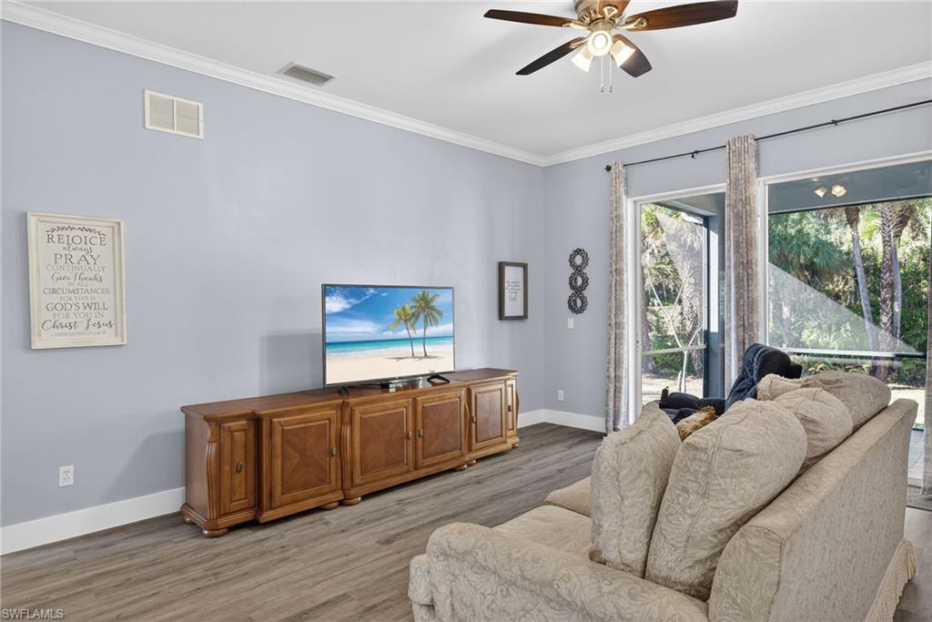 Living room with light wood-style flooring, ornamental molding, and a ceiling fan