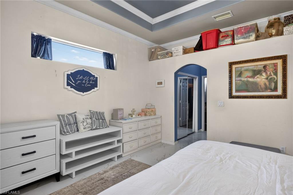 Bedroom featuring arched walkways, ornamental molding, and light marble finish floors