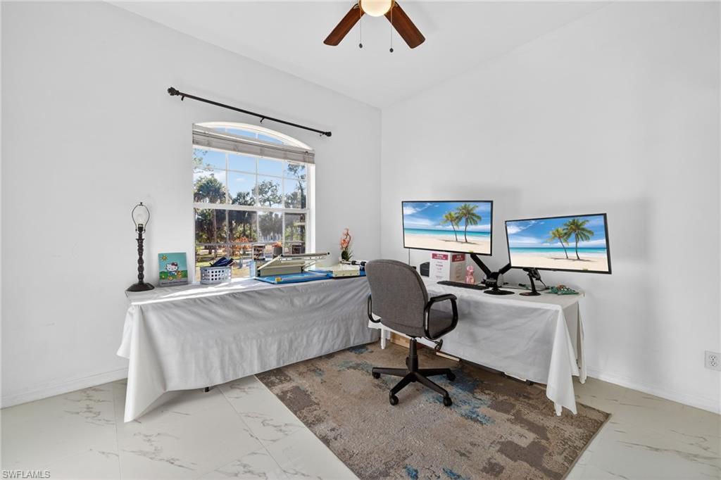 Bedroom with an office area, ceiling fan, light marble finish floors, and lofted ceiling