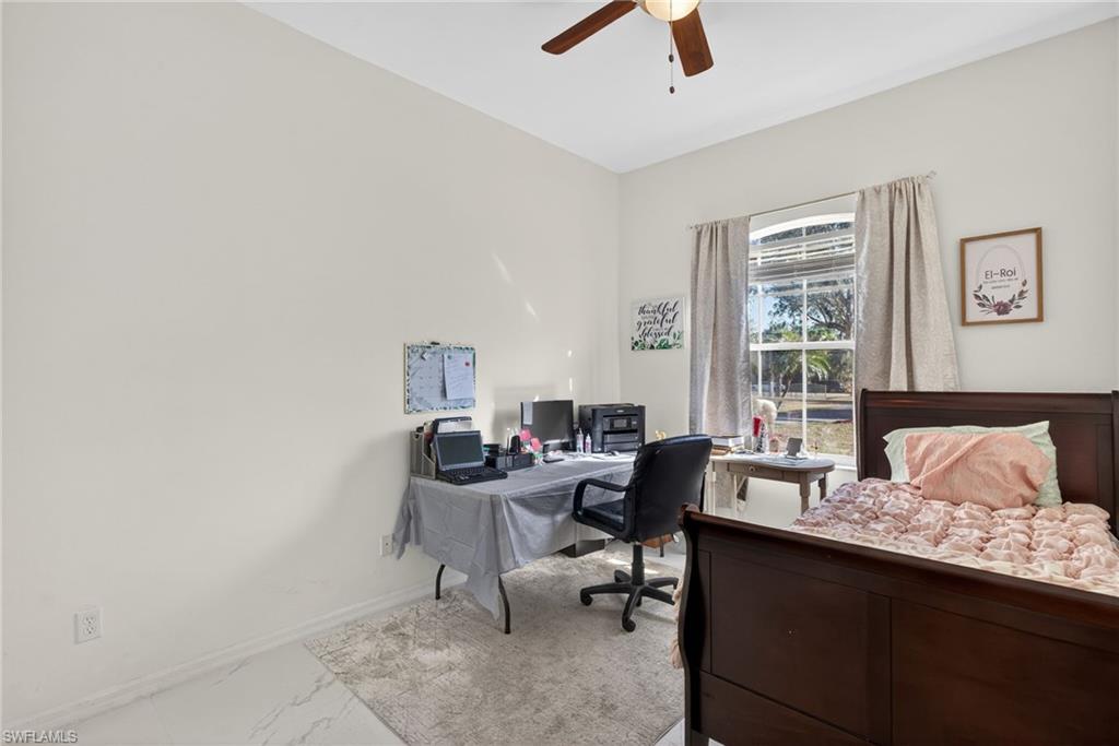 Bedroom featuring a desk, marble finish floors, and ceiling fan